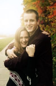 a man and woman hugging each other on a sidewalk