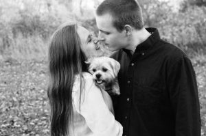 a man and woman kissing with a small dog