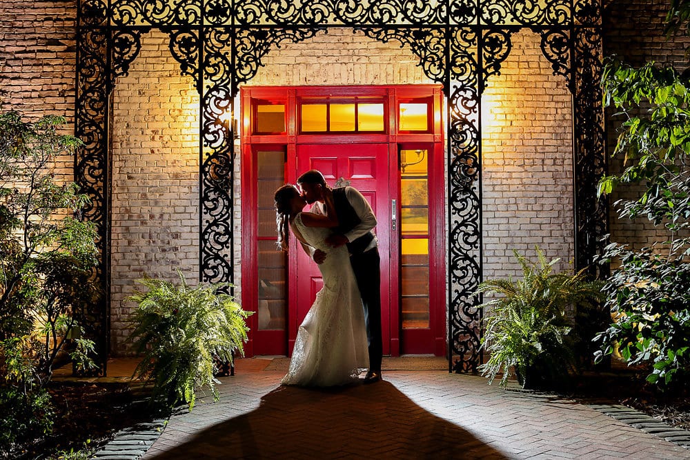 a bride and groom kissing in front of a red door
