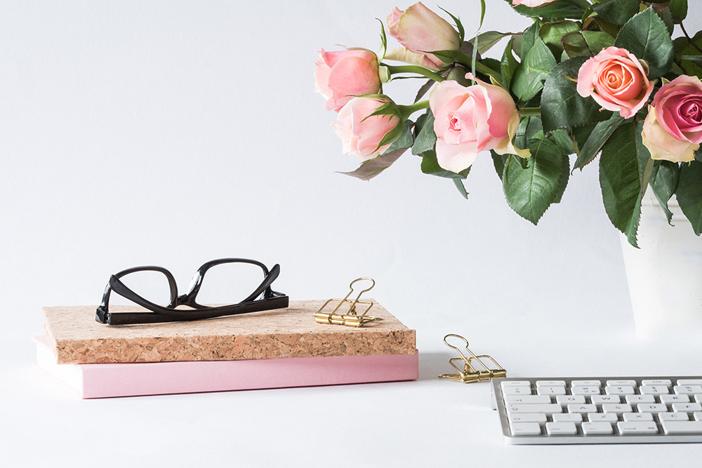 a pair of black glasses sitting on top of a book next to a keyboard