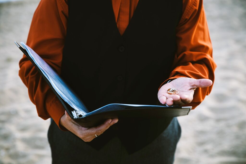 a man in an orange shirt and black vest holding a binder