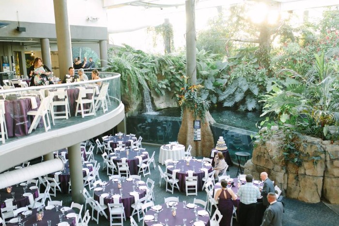 a group of people standing around tables with purple tablecloths