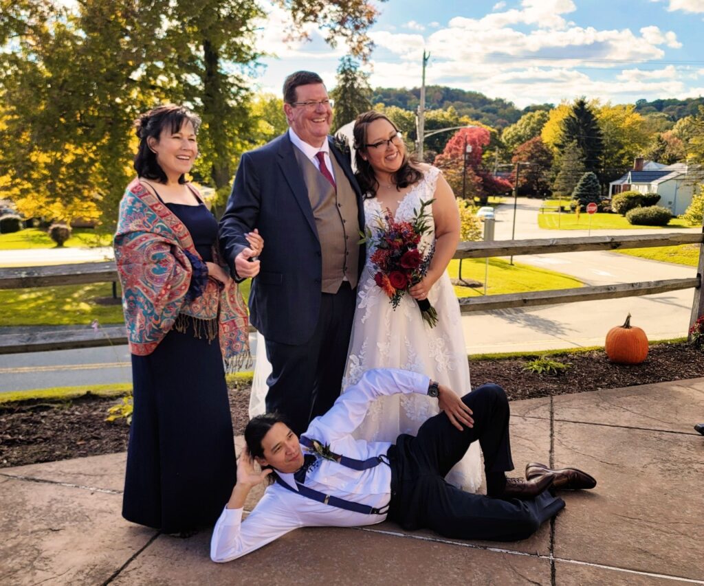 a bride and groom pose for a photo with their family