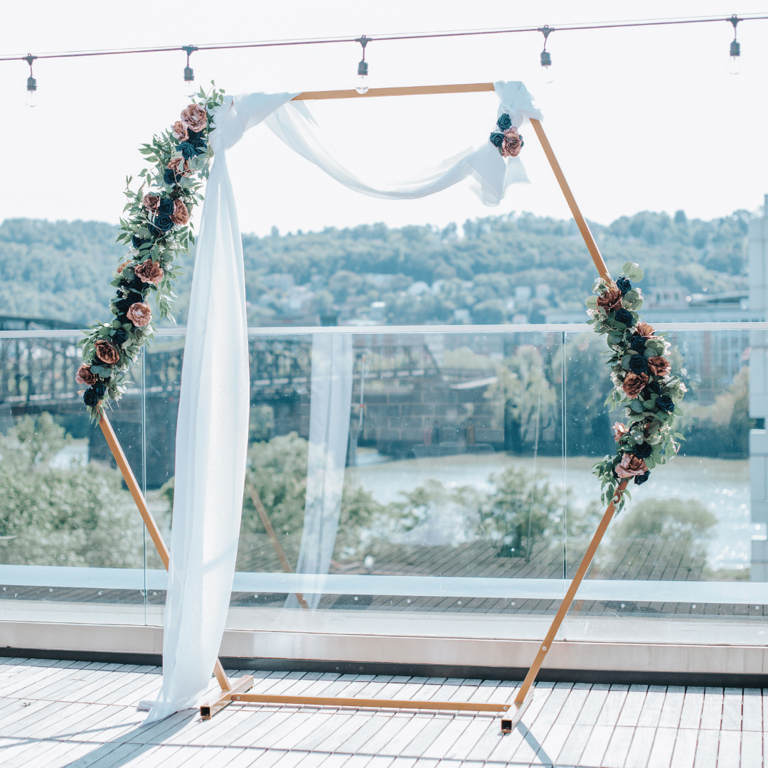 a wedding wooden hex arch decorated with flowers and greenery