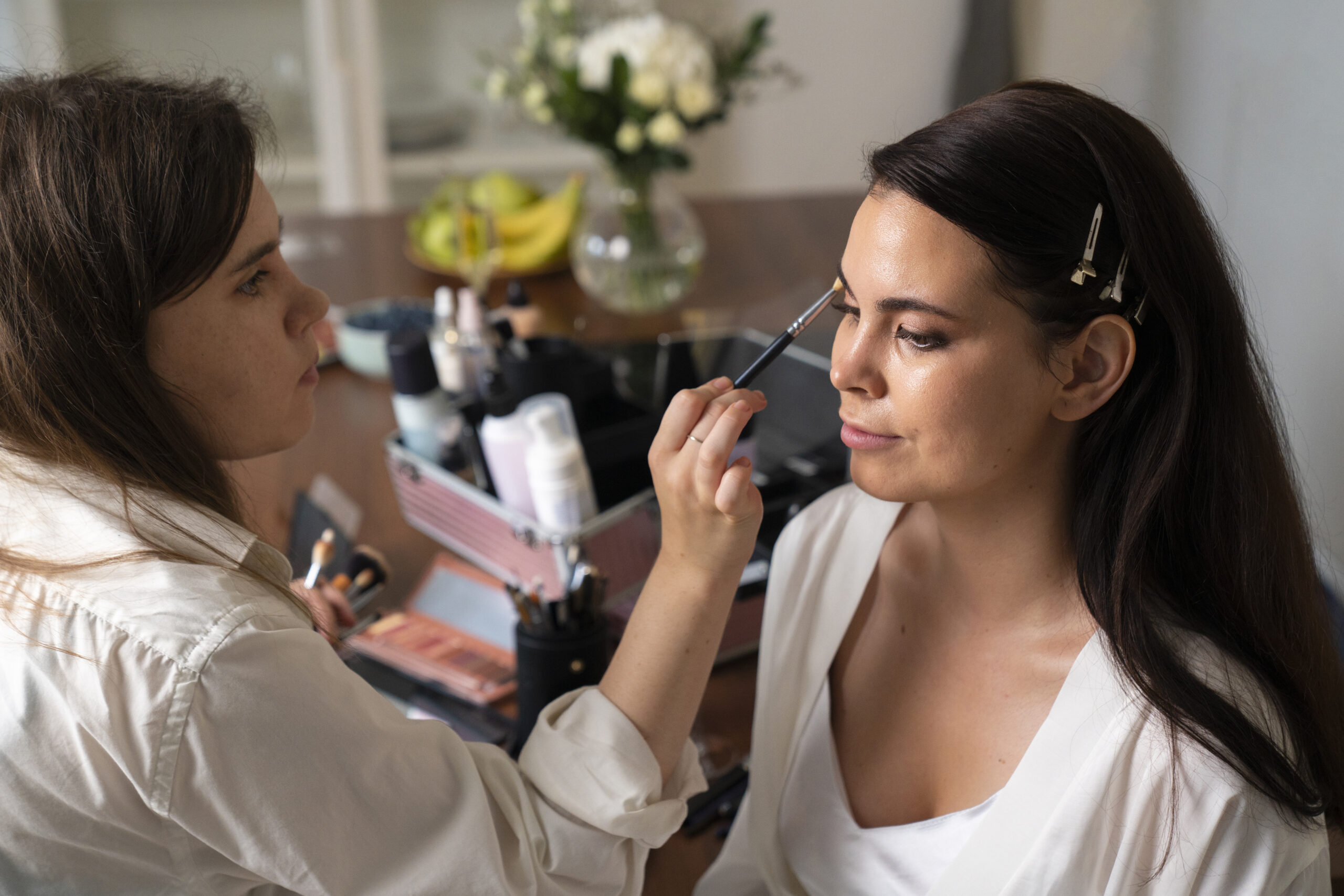 a woman getting her make up done by another woman