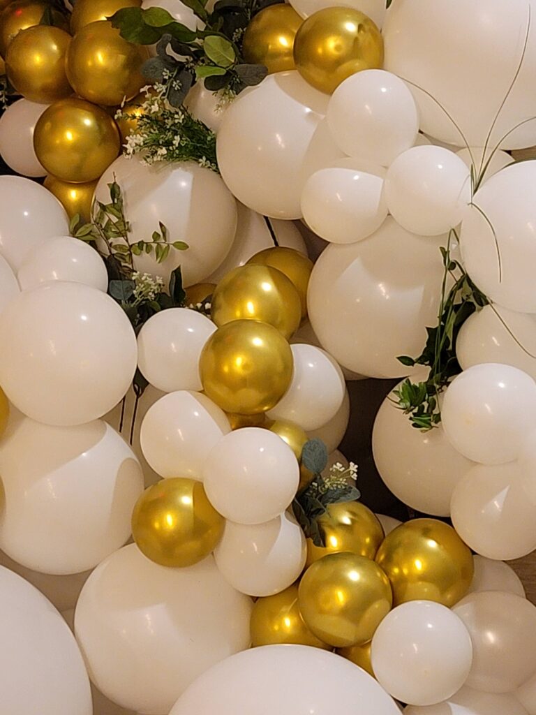 white and gold balloons with greenery on them