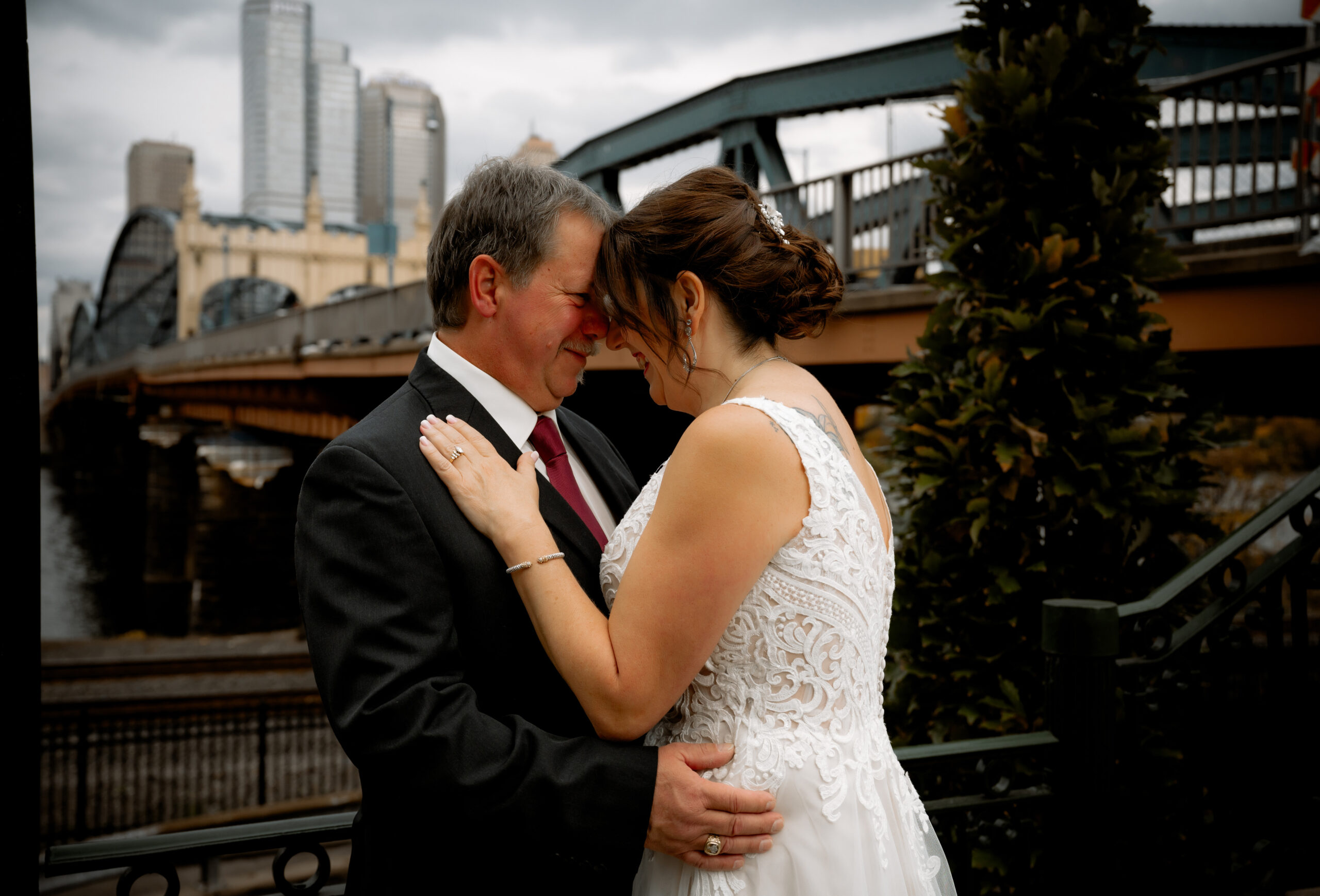 a bride and groom embracing in front of a bridge