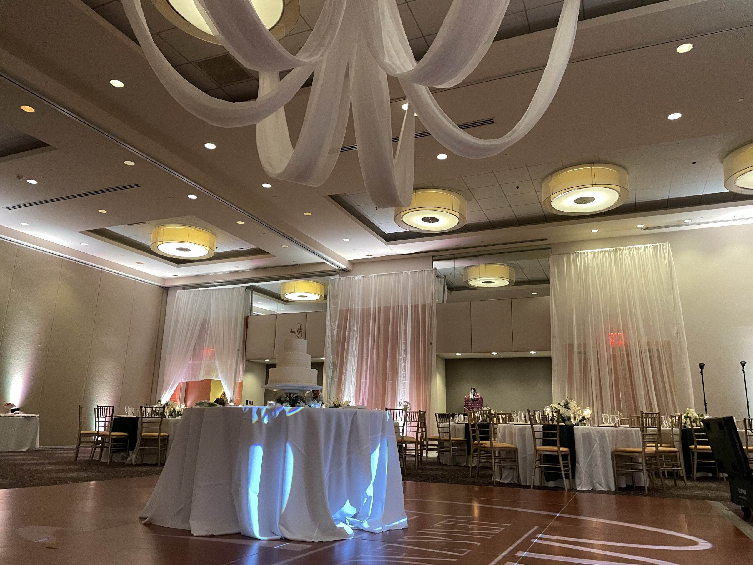 a banquet hall with white drapes hanging from the ceiling